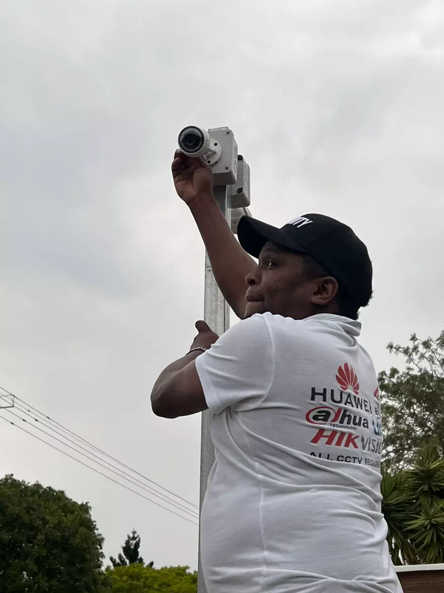 Technician installing a CCTV security camera on an outdoor pole